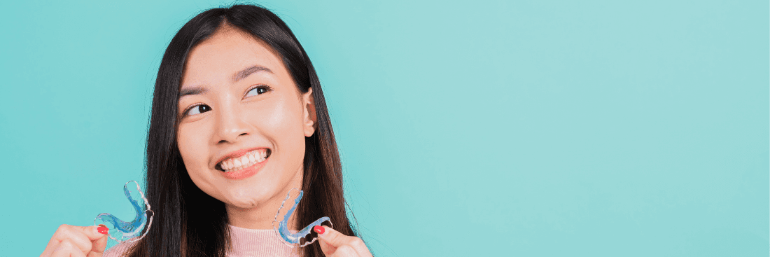 Smiling woman holding clear aligners in North Tampa