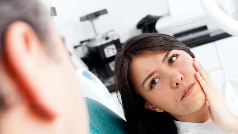 woman with sensitive teeth on a dental chair