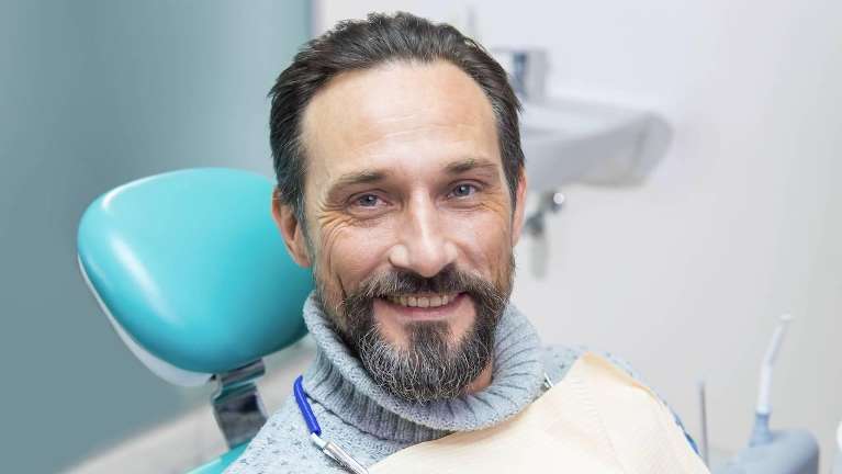 A middle aged man with a relaxed expression is comfortably seated on a modern dental chair 