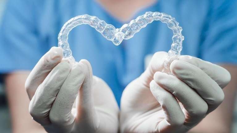 Dentist holding a pair of clear aligners in Tampa